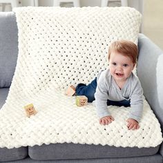 a baby laying on top of a couch next to wooden blocks