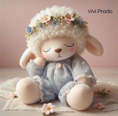 a stuffed animal wearing a blue dress with flowers on it's head sitting on a lace doily