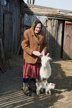 an old woman is petting a small goat