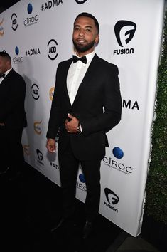 a man in a tuxedo standing on a red carpet