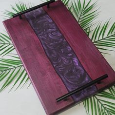 a wooden board with two chopsticks on it and some green leaves around it