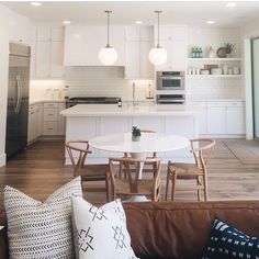 a living room filled with furniture next to a kitchen and dining room table on top of a hard wood floor