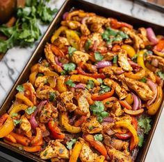 chicken fajita in a pan with cilantro and red peppers on the side