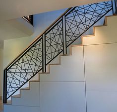 a stair case in the corner of a room with white walls and black railings