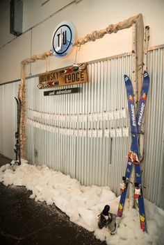 two skis are propped up against a wall with snow on the ground below them