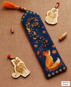 a cross - stitch bookmark with an embroidered fox and other items on the table