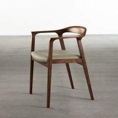 a wooden chair sitting on top of a carpeted floor next to a white wall