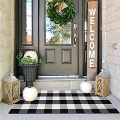 a front door with a welcome mat and two pumpkins