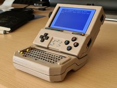 an old computer sitting on top of a wooden table next to a book and pen