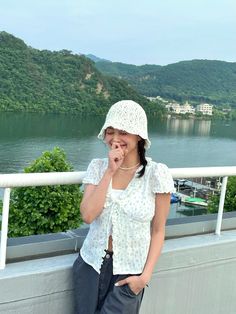 a woman standing on top of a balcony next to a lake and mountains in the background