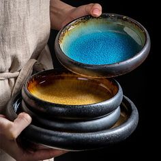 a person holding three bowls with blue and yellow powder in them