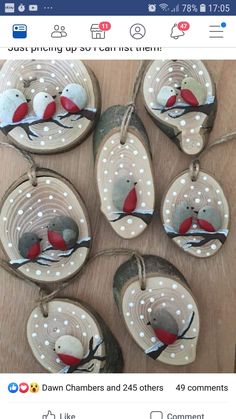 six handmade ornaments with red and grey birds hanging from strings on a wooden table