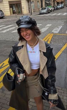 a woman is standing on the street with her hand in her pocket and wearing a hat