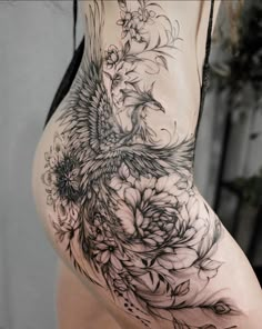 a woman's back with flowers and birds tattoo on the side of her body