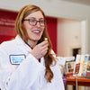 a woman in white lab coat holding something up to her mouth