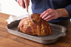 a person cutting into a loaf of bread on top of a metal baking pan with a knife in it