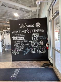 a chalkboard sign in front of a gym with the words welcome to anytime and fitness written on it