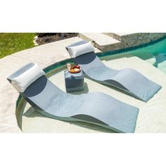 two lounge chairs sitting on top of a swimming pool next to a small table with food