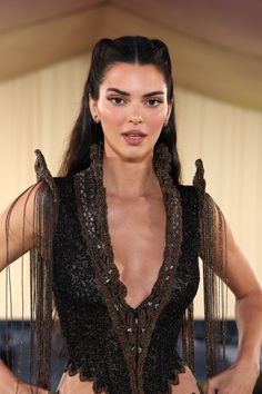 a woman with long hair wearing a black and brown outfit is posing for the camera