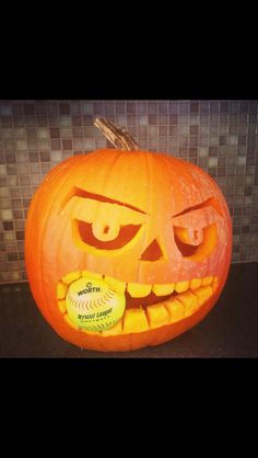 a carved pumpkin with a baseball in it's mouth