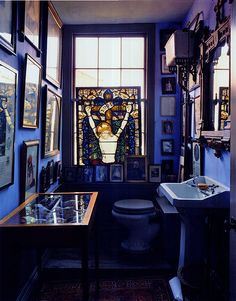 an old fashioned bathroom with stained glass windows and pictures on the wall, along with a toilet