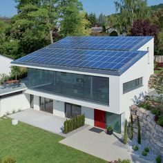 an aerial view of a modern house with solar panels on the roof and in the yard