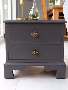 a grey dresser with two drawers and a plant on top