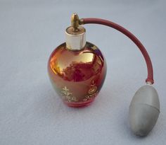 a red and gold glass bottle sitting on top of a white surface