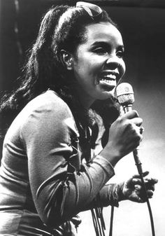 a black and white photo of a woman singing into a microphone