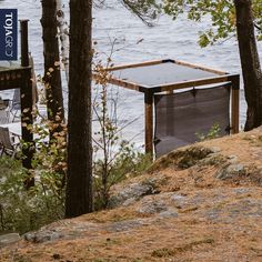 an outhouse on the edge of a lake surrounded by trees and rocks with a sign that reads 1011