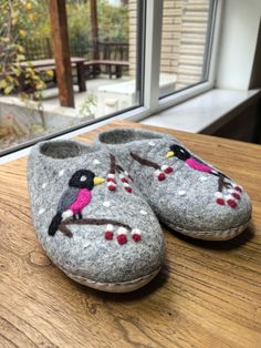 a pair of slippers with birds on them sitting on a table next to a window