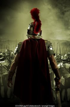 a man in a red cape and helmet standing next to a group of men with spears