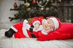 a baby dressed as santa claus sleeping on a pillow