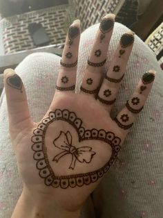 a woman's hand with henna tattoos on it and a heart shaped design