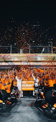 a group of people standing around each other on top of a race track with confetti in the air