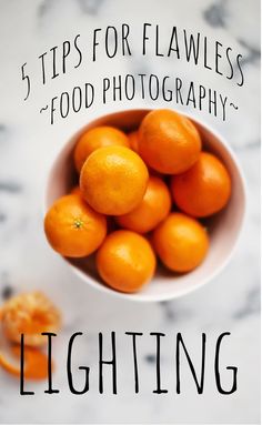 a white bowl filled with oranges on top of a table