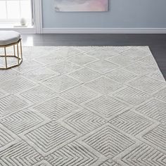 a white rug with diamond pattern on the floor in front of a blue painted wall