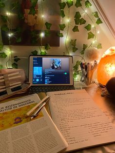 an open book sitting on top of a desk next to a laptop computer and lamp