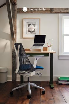 a desk with a laptop on top of it in a room next to a window