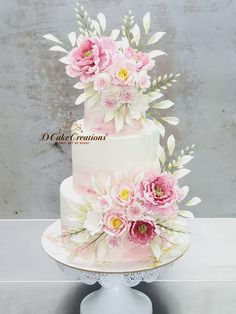 a three tiered cake with pink flowers and leaves on the top is sitting on a white pedestal