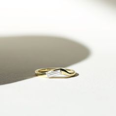 a yellow gold ring with a baguette cut in the middle on a white surface