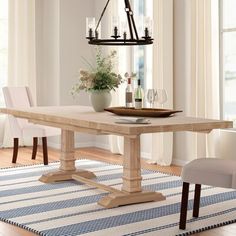 a dining room table with two chairs and a vase on the rug in front of it