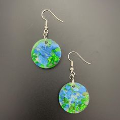 Elevate your style with these one-of-a-kind resin circular earrings, featuring a harmonious blend of blue and green hand-dyed shells set against a clear, white background. The circular shape embodies unity and eternal beauty, while the calming blue and refreshing green hues evoke tranquility and renewal. Handcrafted with care, these unique earrings offer a touch of serene elegance and meaningful artistry.  Materials: Crafted from hypoallergenic, crystal-clear resin, these earrings ensures both c Artistic Multicolor Hypoallergenic Jewelry, Artistic Blue Nickel-free Jewelry, Artsy Nickel-free Blue Jewelry, Artsy Blue Nickel-free Jewelry, Artisan Green Earrings With Artistic Design, Handmade Artistic Blue Earrings, Artsy Blue Dangle Earrings, Artistic Blue Earrings As Gift, Adjustable Blue Jewelry With Artistic Design