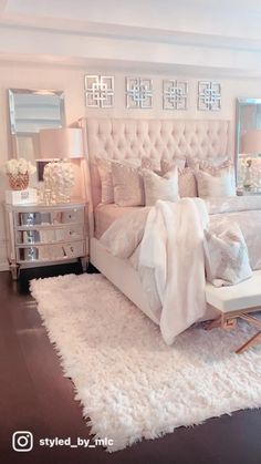 a white bedroom with a large bed and lots of pillows on the top of it