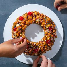 two hands are decorating a cake with sprinkles on a white plate