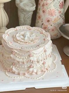 a three tiered cake sitting on top of a white plate next to vases