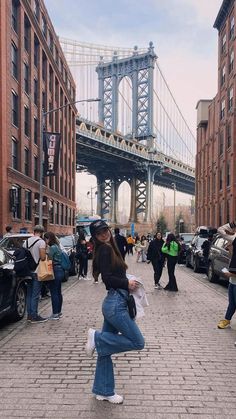 a woman is walking down the street in front of some tall buildings and a bridge