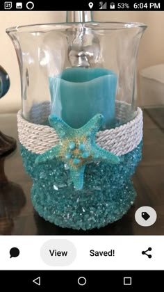 a blue candle holder with a starfish on the front and side, sitting on a table