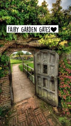 an old wooden gate with vines growing over it and a walkway leading to the entrance