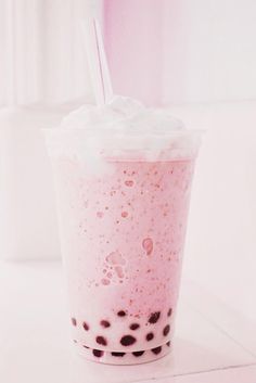 a pink drink with black spots and a straw in it